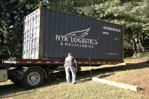 Moveable truck bed slides the container back and down to allow for easy placement.