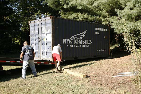 Front log is pulled under the container before it is finally lowered into position.