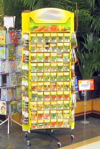Seed rack in store. In bright light, next to card racks and backed by plants. Humidity will be high near the plants and bright light and heat is not ideal for seed viability.