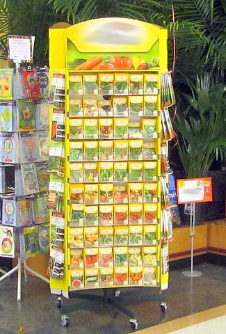 Seed rack in store. In bright light, next to card racks and backed by plants. Humidity will be high near the plants and bright light and heat is not ideal for seed viability.
